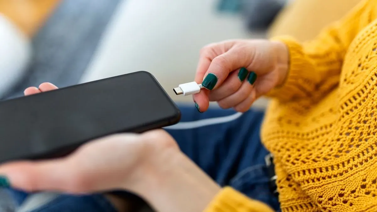 Person steckt Ladekabel in Smartphone