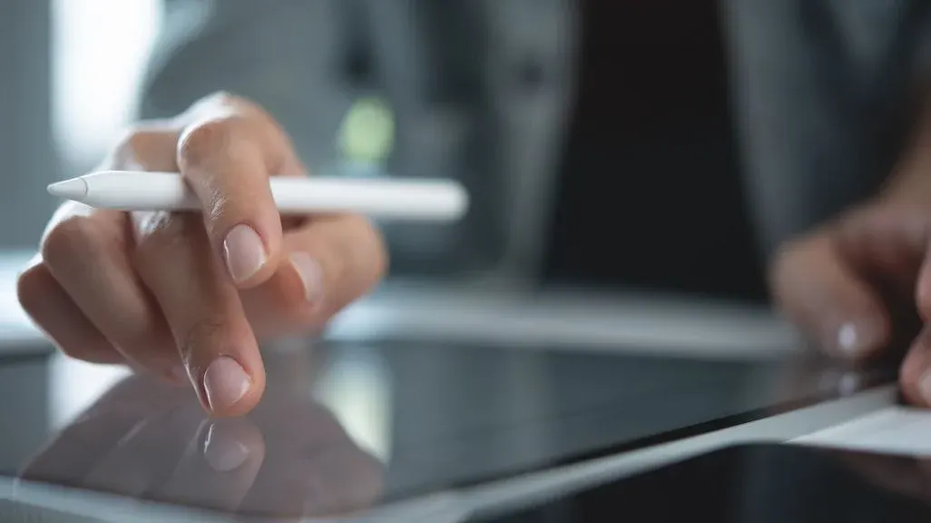 Ein Benutzer tippt auf dem Bildschirm eines Tablets, der Eingabestift ist zwischen den Fingern eingeklemmt.