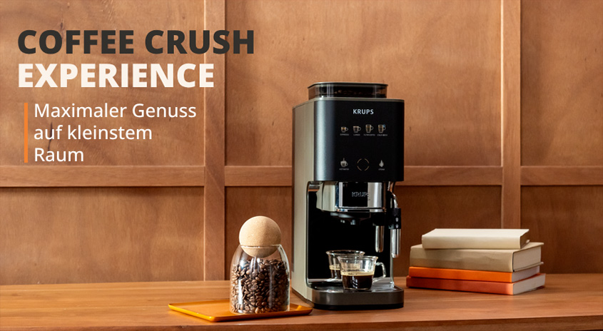 COFFEE CRUSH EXPERIENCE: Krups Kaffeemaschine mit Kaffee-Behälter und Büchern auf Holztisch. Maximaler Genuss auf kleinstem Raum.