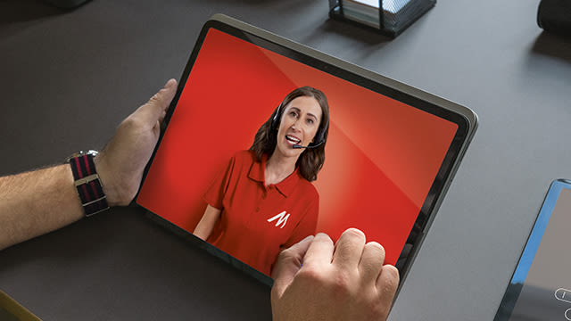 Ein Mann hält ein Tablet in der Hand. Im Screen des Tablets sieht man ein Frau aus dem MediaMarkt Callcenter in einem roten T-Shirt mit weißem MediaMarkt Logo. Die Frau trägt ein Headset und spricht mit dem Kunden, der das Tablet in den Händen hält.