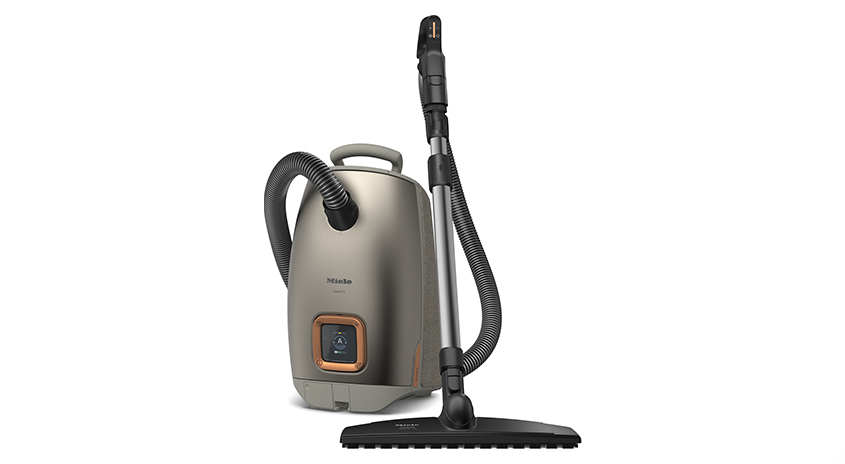 Ein Staubsauger mit einem zylinderförmigen Körper und einem Schlauch steht auf einem weißen Hintergrund.