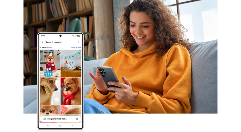Eine Frau in einem orangefarbenen Hoodie sitzt auf einem Sofa und benutzt ein Smartphone, auf dem Suchergebnisse für Hundebilder angezeigt werden. Im Hintergrund ein Bücherregal.