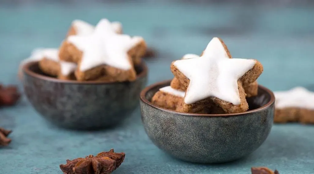 Zimtsterne mit weißem Zuckerguss in kleinen Schalen angerichtet.