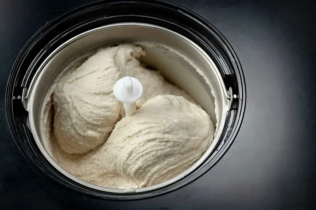 Kokosnusseis liegt in der Schüssel einer geöffneten Eismaschine.