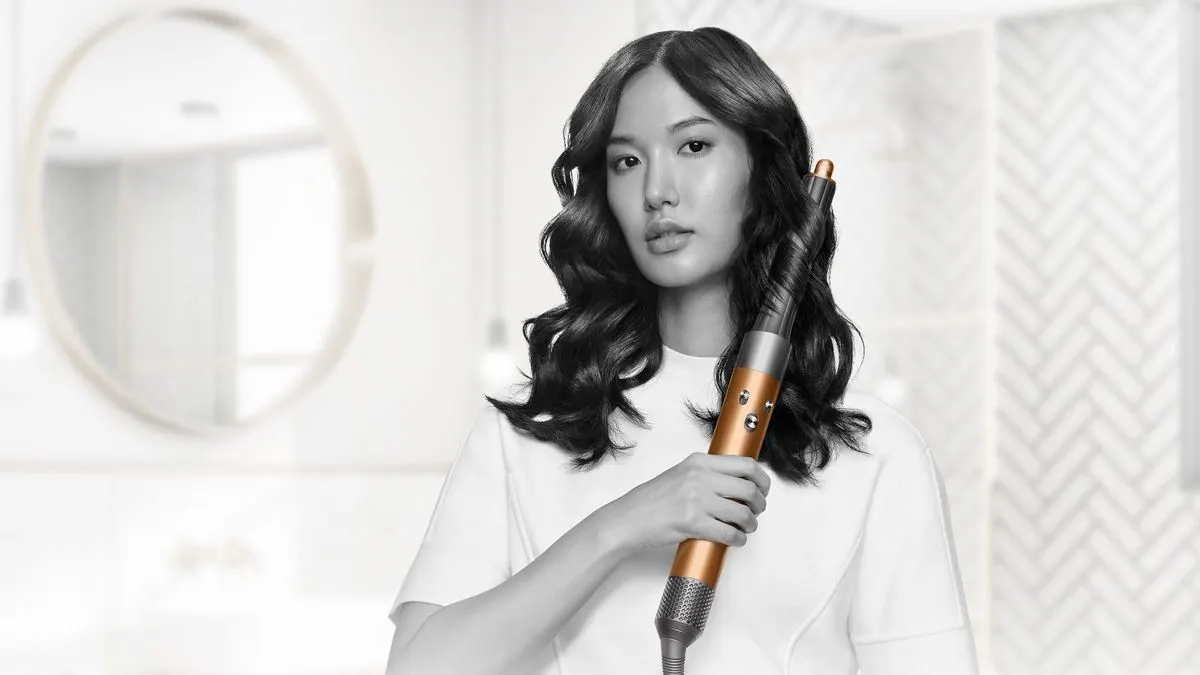 Eine Frau mit lockigem Haar verwendet einen Dyson Airwrap