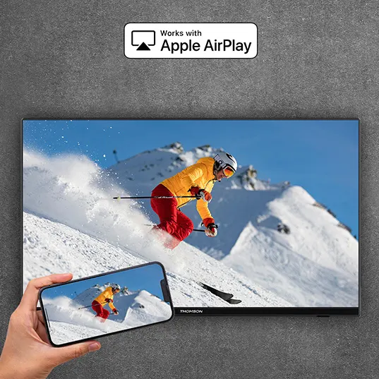 Auf dem Bildschirm eines Fernsehers ist ein Skifahrer zu sehen. Ein Mobiltelefon zeigt das gleiche Bild. Oben steht "Works with Apple AirPlay".