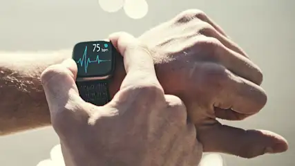 Hand legt Smartwatch mit Herzfrequenzanzeige an das Handgelenk an.