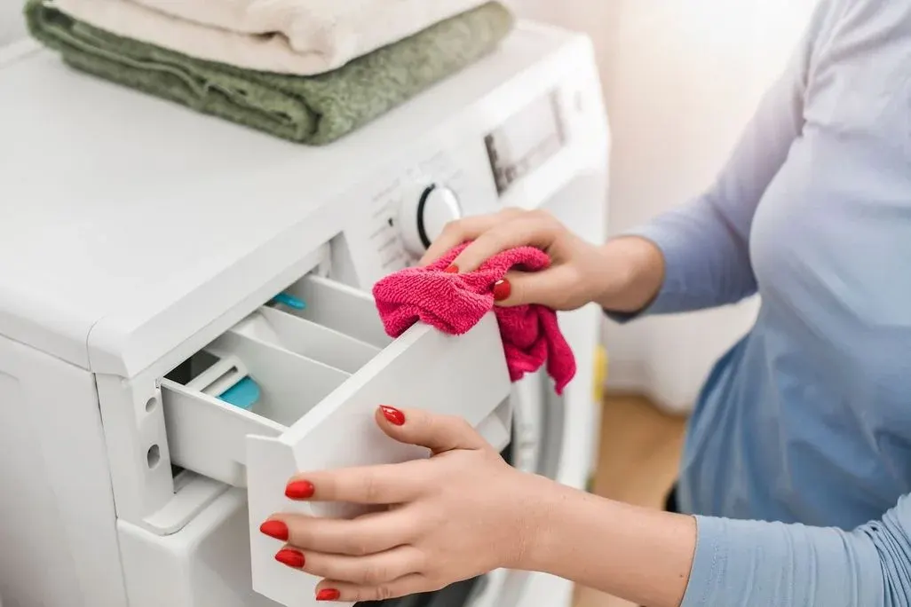 Bild zeigt eine Person die eine Waschmittelschublade reinigt