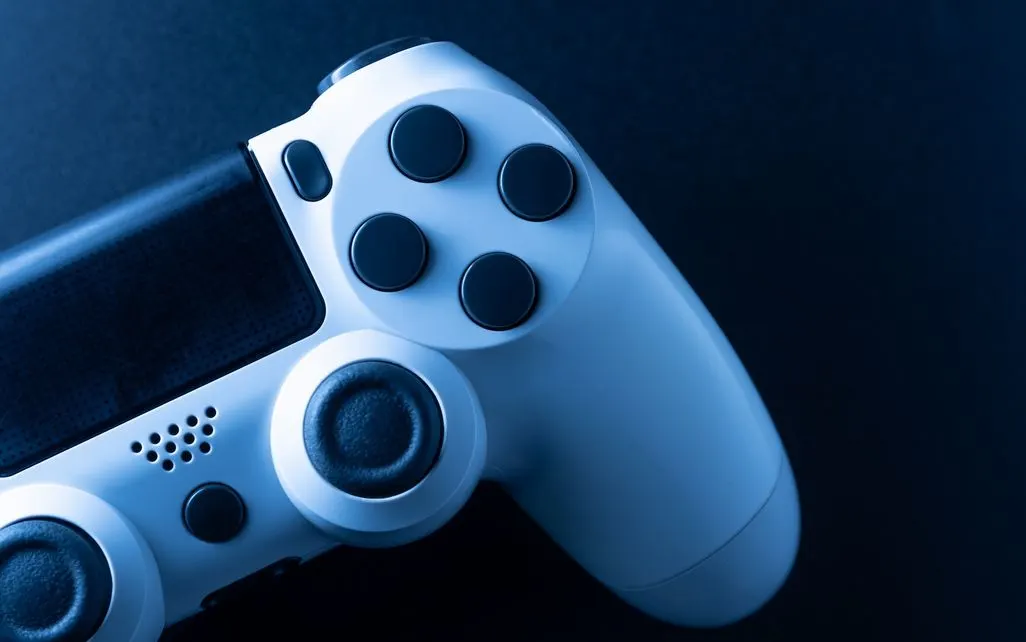 Weißer Gamecontroller liegt auf dunklem Hintergrund.