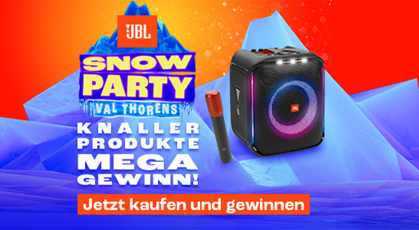 Ein JBL-Lautsprecher, ein Mikrofon und ein Werbebanner für eine „Snow Party“ vor blau-orangem Hintergrund.