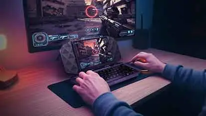 Hände bedienen einen Project DualPlay Mini, der auf einem Gamingtisch vor einem Bildschirm steht.