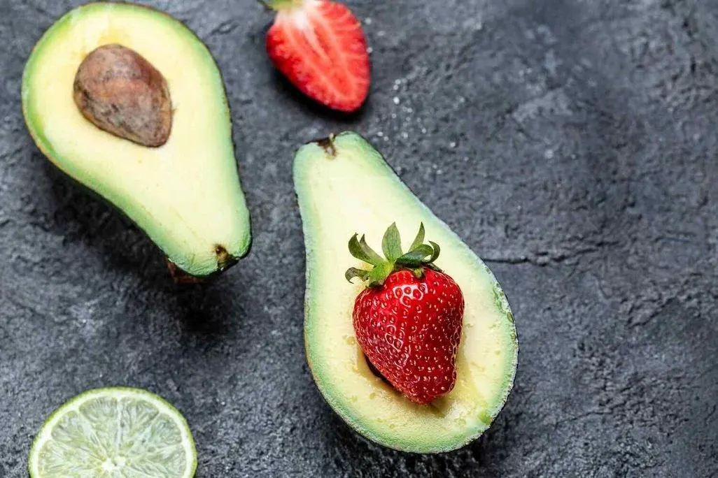 Halbiere Avocodos bei denen in eine Hälfte statt des Kerns eine Erdbeere eingesetzt ist.