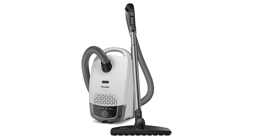 Ein weißer Staubsauger mit grauem Schlauch und schwarzem Aufsatz steht auf einem weißen Hintergrund.