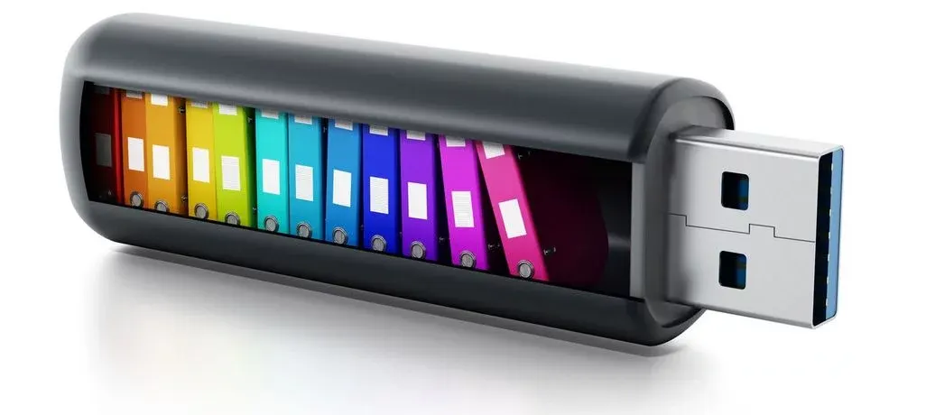USB-Stick mit durchsichtiger Hülle und farbigen Speicherbausteinen in Regenbogenfarben.