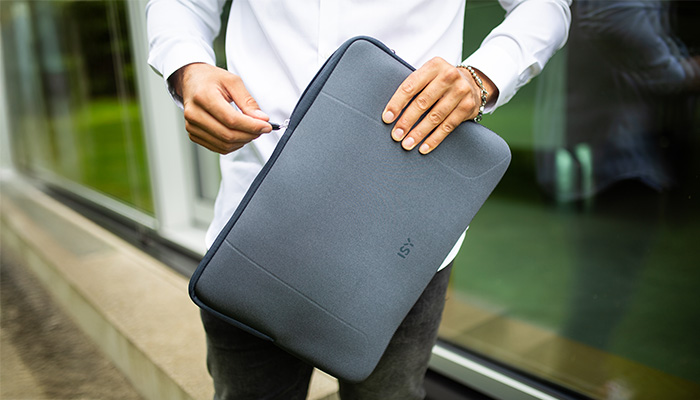 Person in weißem Hemd hält eine graue ISY Laptop-Tasche (Sleeve)  in beiden Händen im Freien.