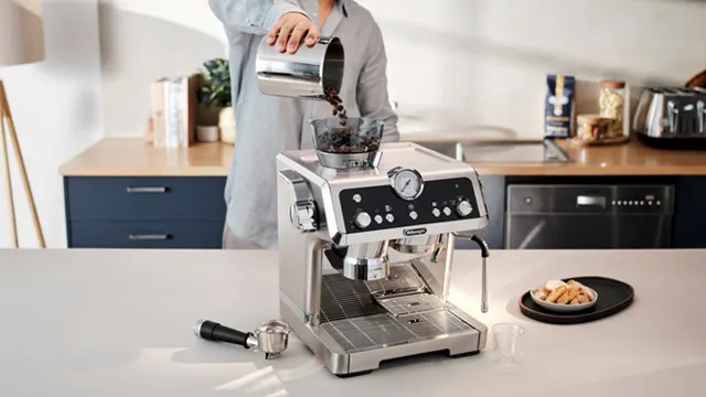 Eine silberne Kaffeemaschine auf einer weißen Küchentheke, Bohnen werden hineingegossen.