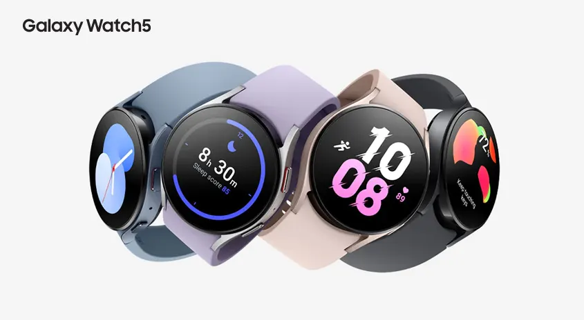 Vier Samsung Galaxy Watch5 Smartwatches mit verschiedenen Armbandfarben zeigen unterschiedliche Zifferblätter.