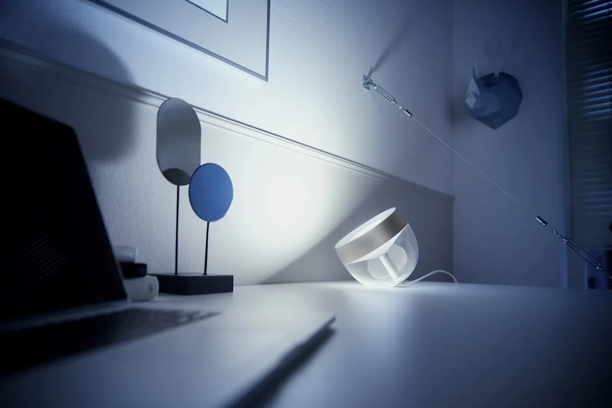 Leuchte Iris von Philips Hue steht auf einem Schreibtisch und beleuchtet die Wand.