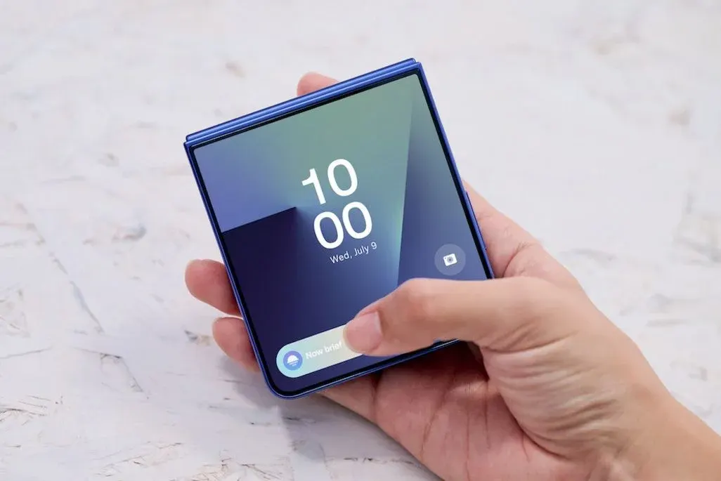 Hand hält gefaltetes Samsung Galaxy Z Fold 7 (blau) im kompakten Zustand; Display zeigt 10:00, Daumen berührt Bildschirm.