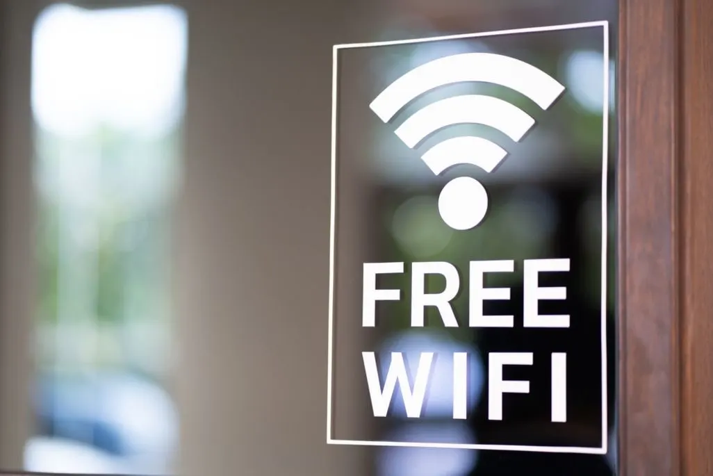 Ein Schild mit der Aufschrift Free Wifi ist an einer Glasscheibe angebracht.