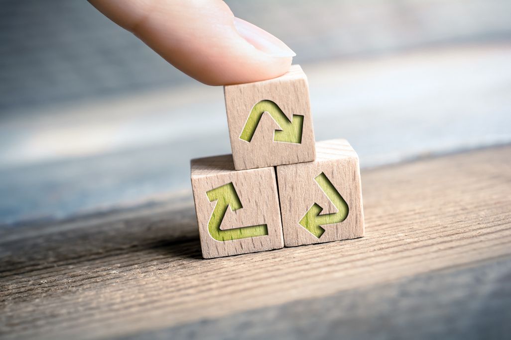 Drei Holzwuerfel mit Recycling Symbol werden zu einem Turm gestapelt