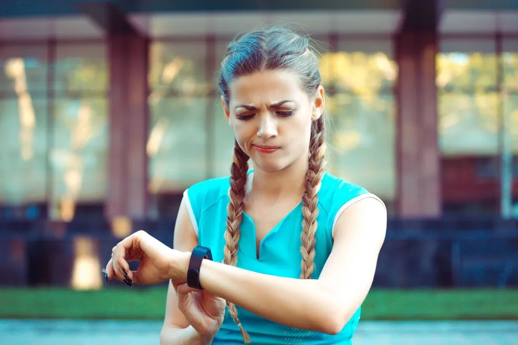 Frau mit Zopf-Flechtfrisur in blauer Sportkleidung bedient eine schwarze Smartwatch