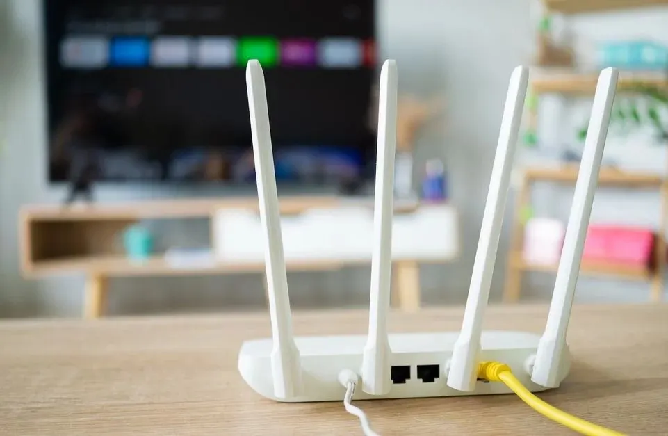 Router mit vier Antennen, im Hintergrund ein Fernseher.