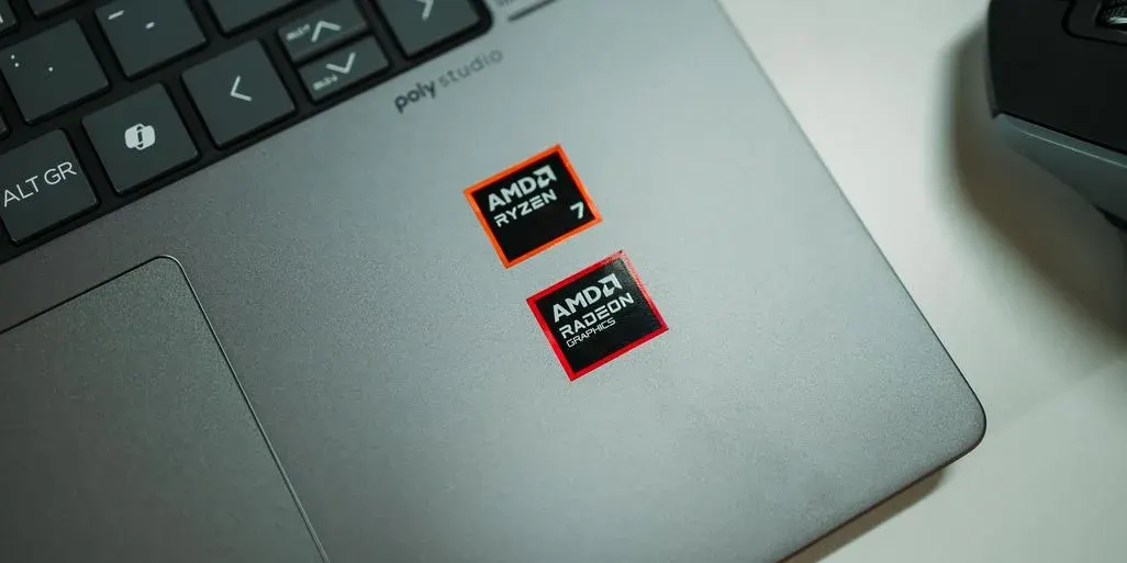 Grauer Laptop mit schwarzer Tastatur und Trackpad. Zwei Aufkleber: ein orange-schwarzer AMD Ryzen 7 und ein rot-schwarzer AMD Radeon Graphics.