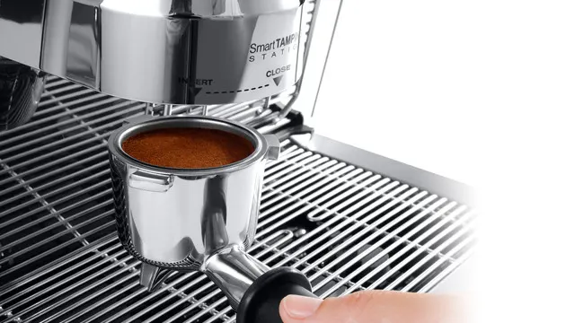 Detailaufnahme einer silbernen Espressomaschine mit einem Siebträger voller Kaffee.
