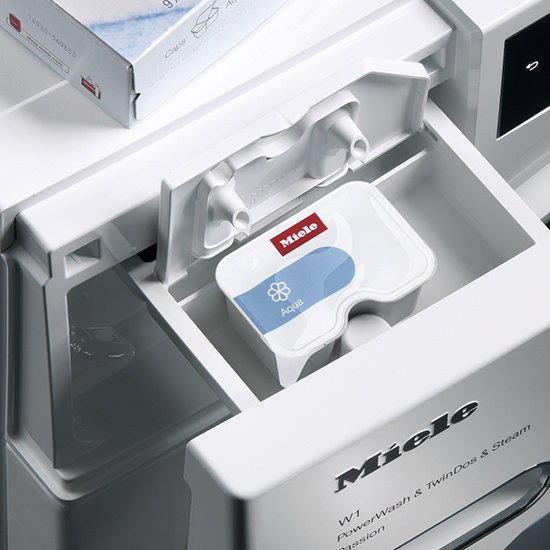 Nahaufnahme einer weißen Miele Waschmaschine mit Waschmittelbehälter und blauem Aqua-Etikett.