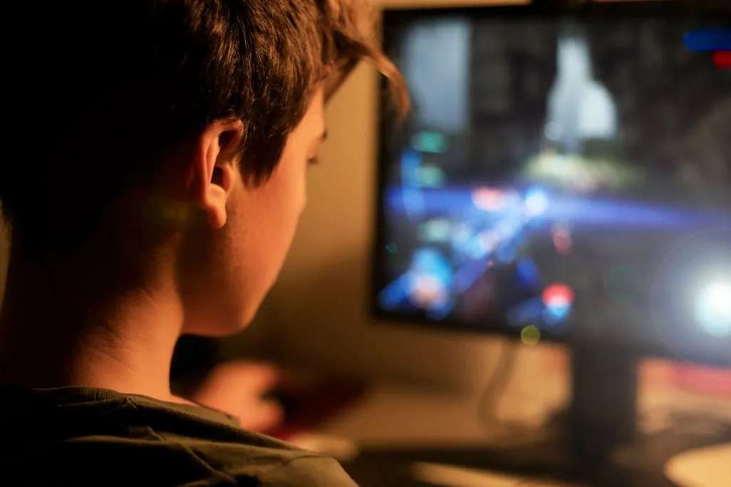 Person sitzt vor einem Bildschirm und spielt ein Videospiel