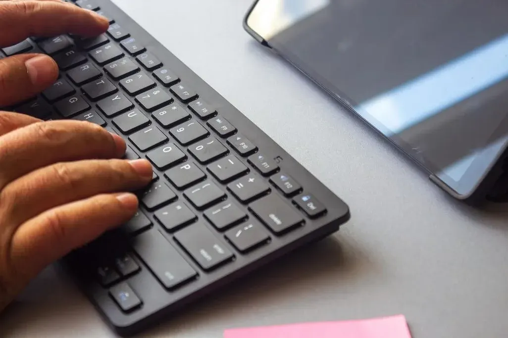 Hand tippt auf Bluetooth-Tastatur, die vor einem Tablet liegt.