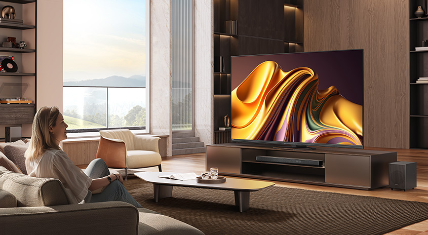 Ein Wohnzimmer mit einem großen Fernseher, einem Couchtisch und einem Sofa auf einem braunen Teppich.