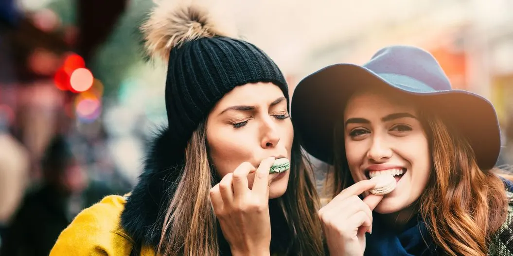 Zwei Frauen mit langen Haaren und Wintermützen posieren nebeneinander im Freien.