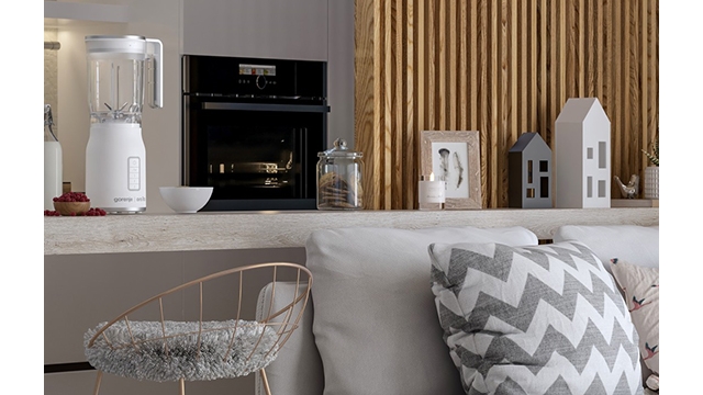 Ein Innenraum mit Mixer, Ofen und Deko-Elementen auf einer Theke. Darunter ein Stuhl und Kissen auf einem Sofa.