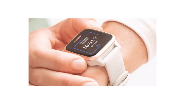 Eine Nahaufnahme einer weißen Smartwatch am Handgelenk, die 15:01 Uhr anzeigt.