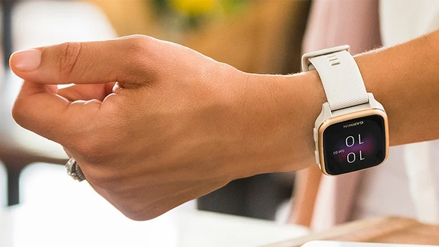 Eine Hand mit einem silbernen Ring und eine weiße Smartwatch mit einem schwarzen Display.