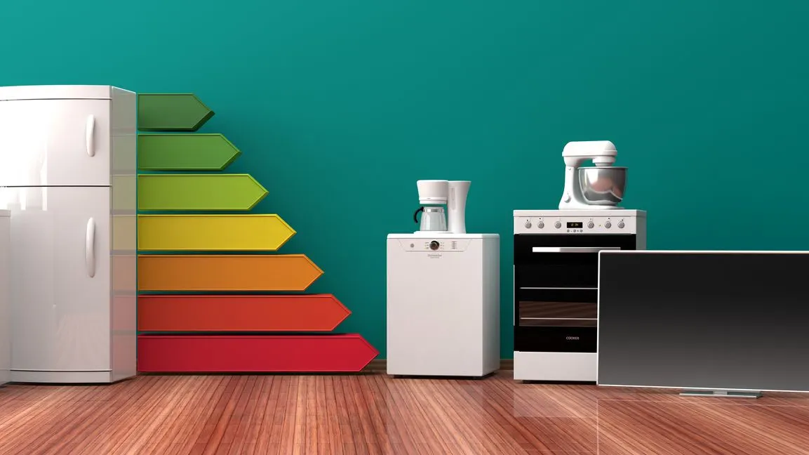 Mehrere Haushaltsgeräte stehen vor einer farbigen Energieeffizienzskala.