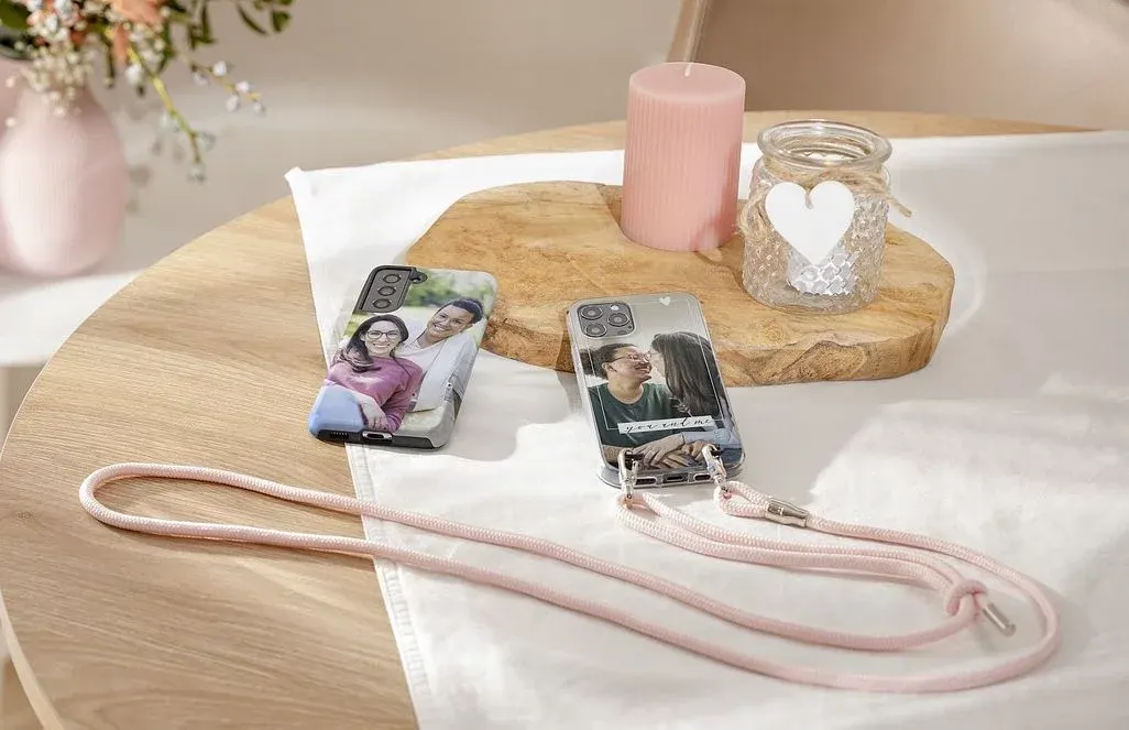 Zwei Handyhüllen mit Fotos drauf liegen auf einem Tisch mit weißem Tischtuch