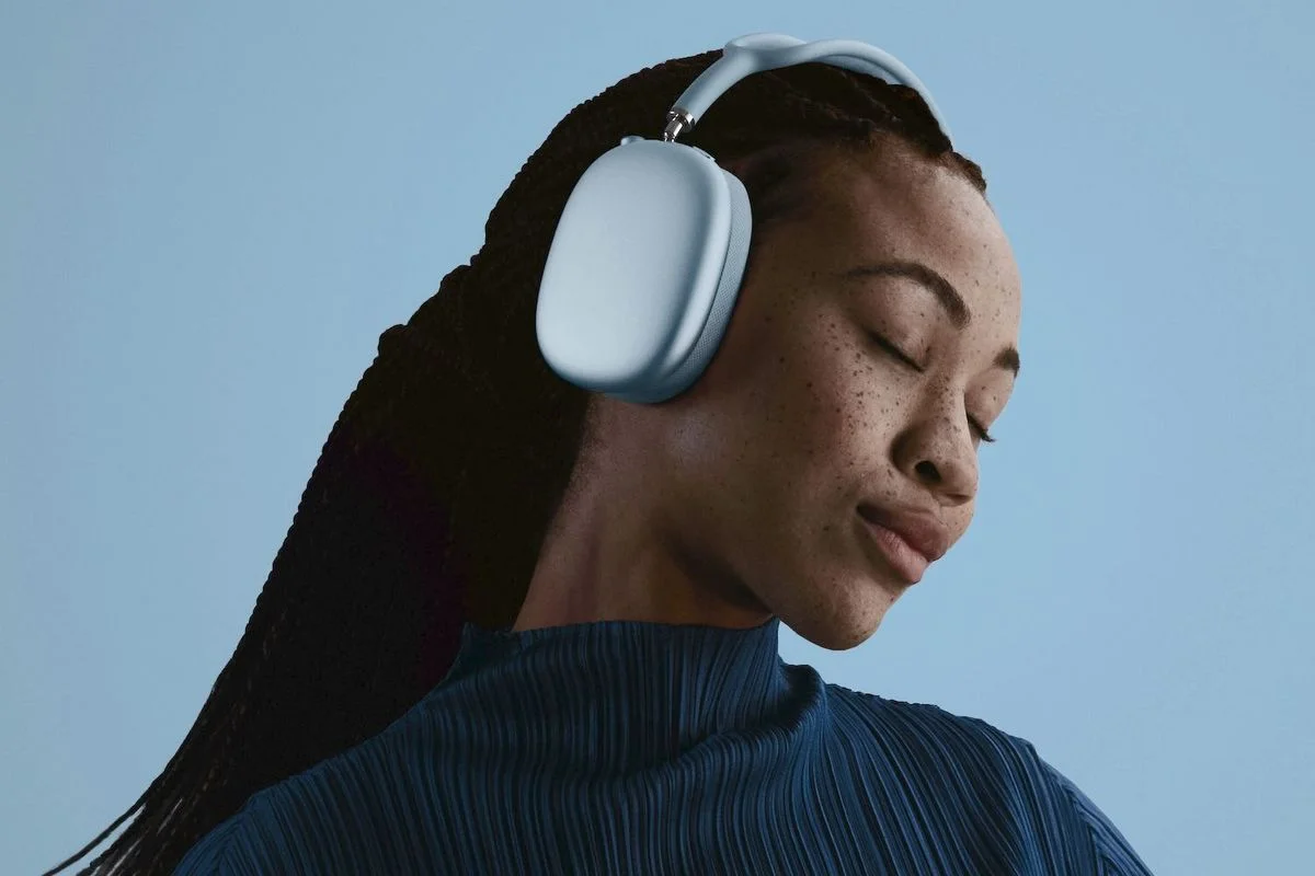 Mann trägt weiße Over-Ear-Kopfhörer mit blauem Hintergrund. Profil-Ansicht, entspannter Ausdruck. Moderne kabellose Audio-Technologie für Musik und Sound.