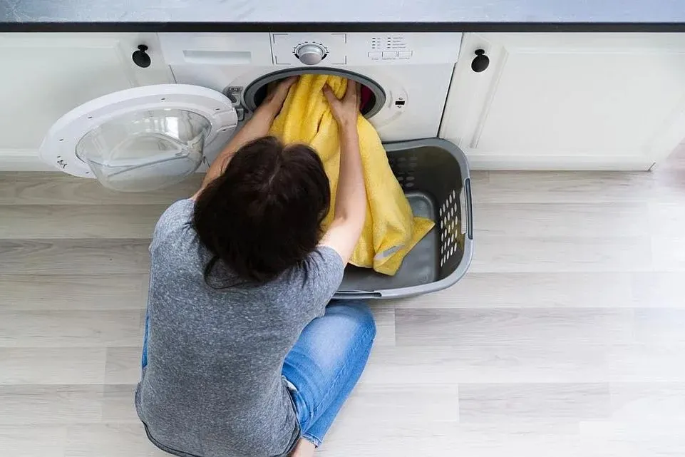 Eine Frau holt ein gelbes Badetuch aus einem Trockner.