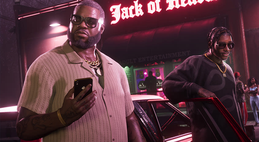 Boobie und Dre'Quan steigen aus einem Auto aus. Boobie hält sein Telefon, während Dre'Quan an der offenen Fahrzeugtür lehnt.