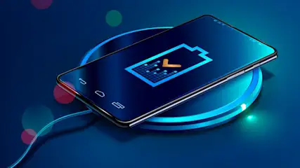 Schwarzes Smartphone auf blau-türkisem, rundem kabellosem Ladepad. Der Bildschirm zeigt blaues Batteriesymbol mit gelbem Haken auf blauem Hintergrund.