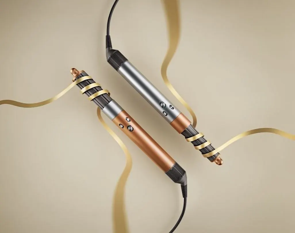Zwei Dyson Airwrap liegen auf beigem Hintergrund, umwickelt mit goldenem Band