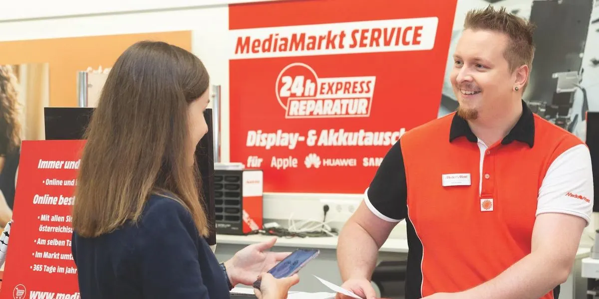 Kundin laesst sich an einer MediaMarkt Smartbar zum Smartphone Reparaturservice beraten