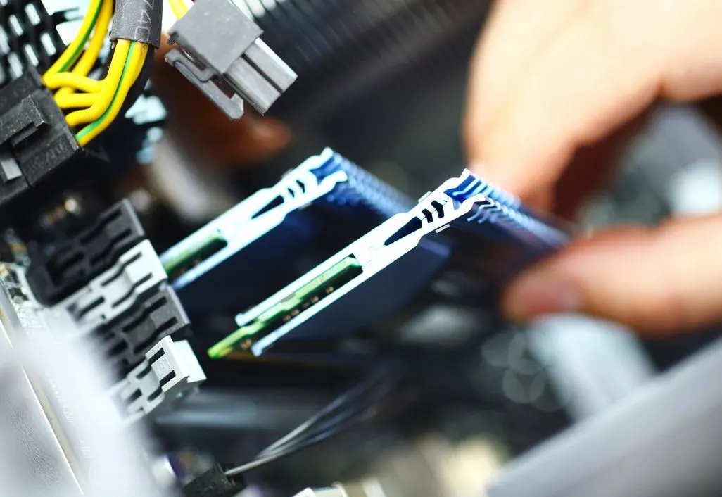 Hand setzt RAM-Speichermodul in Computer-Mainboard mit sichtbaren Kabeln ein