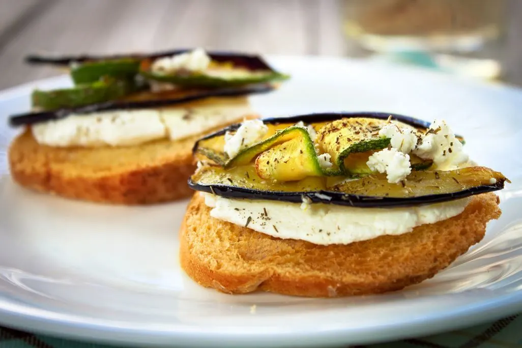 Gerostetes Brot mit Frischkäse Zucchini und Aubergine auf Teller angerichtet