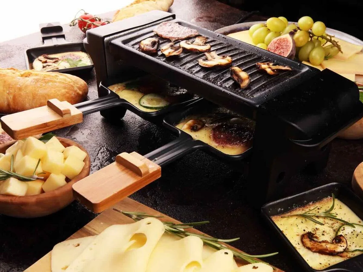 Raclette-Grill mit Schiebern und vielen Zutaten.