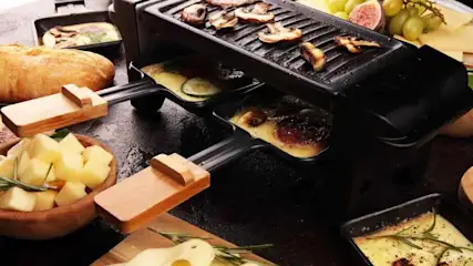 Raclette-Grill mit Schiebern und vielen Zutaten.