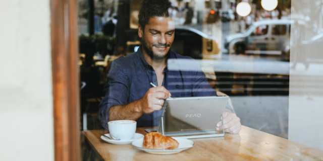 Mensch im Cafe schaut in Notebook